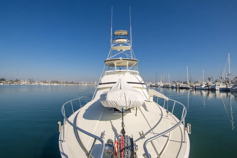Aquila II Yacht Photos Pics 1990 Bertram 50 Convertible yacht docked in a serene marina under clear blue skies.