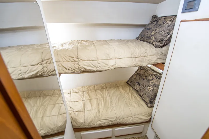Aquila II Yacht Photos Pics Bunk beds in 1990 Bertram 50 Convertible yacht cabin with beige bedding and patterned pillows.