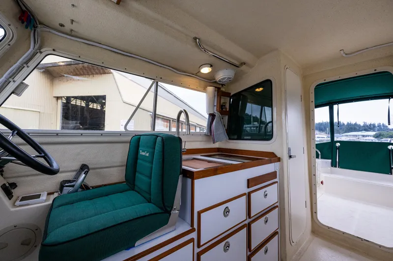 Pretty Penny Yacht Photos Pics Interior of a 2006 C-Dory 25' Tomcat Catamaran with green seating and wooden cabinetry.