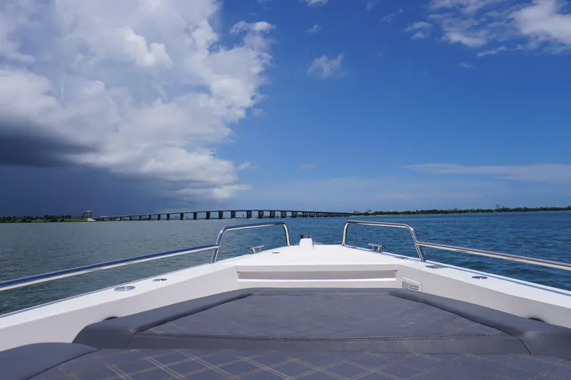 Wanderlust Yacht Photos Pics 2020 Axopar 37 XC Cross Cabin cruising towards a distant bridge under a partly cloudy sky.