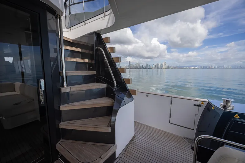 Seahawk Yacht Photos Pics 2025 Azimut Magellano 66 yacht deck with stairs, ocean view, and city skyline.