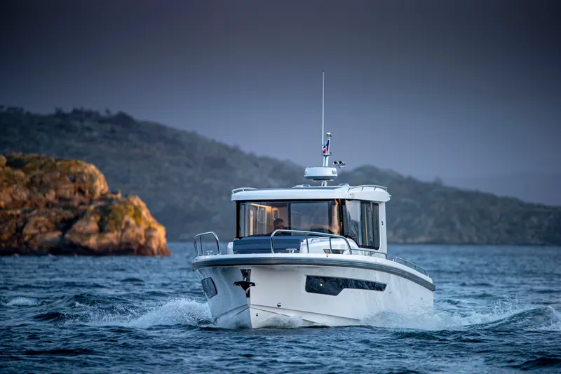  Yacht Photos Pics 2024 Nimbus C11 boat navigating through scenic waters with rocky hills in the background.