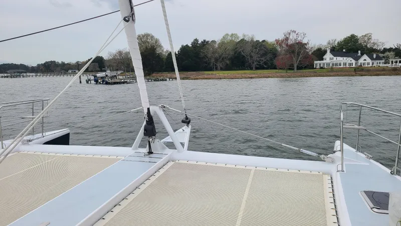 Sovereign Yacht Photos Pics Lidgard Custom Catamaran 2006 on calm waters near a scenic shoreline with houses.