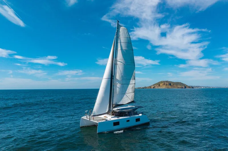 Nostos Yacht Photos Pics Sailing catamaran Nautitech 40 Open 2020 on open sea with island in background.