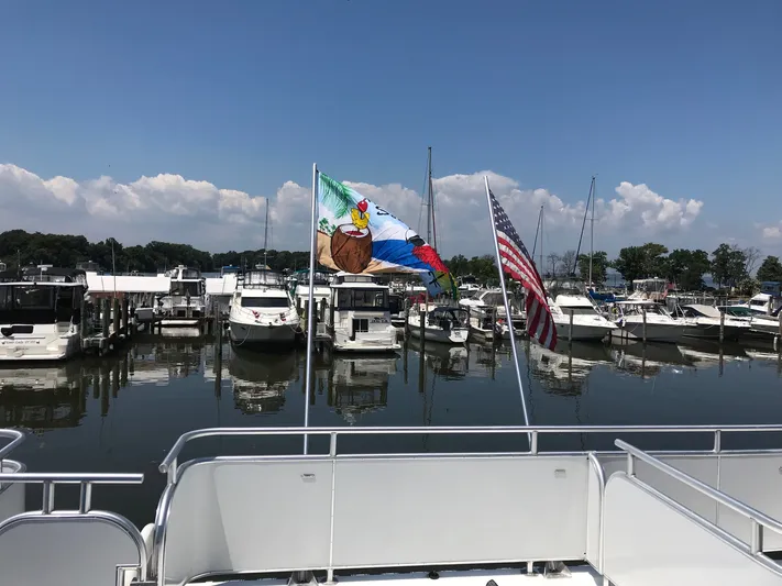St. Somewhere Yacht Photos Pics Houseboats docked at marina, view from 2017 Sumerset houseboat, flags waving under clear sky.