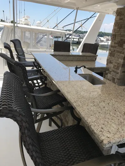 St. Somewhere Yacht Photos Pics Outdoor bar area on a 2017 Sumerset houseboat with granite countertop and wicker chairs.