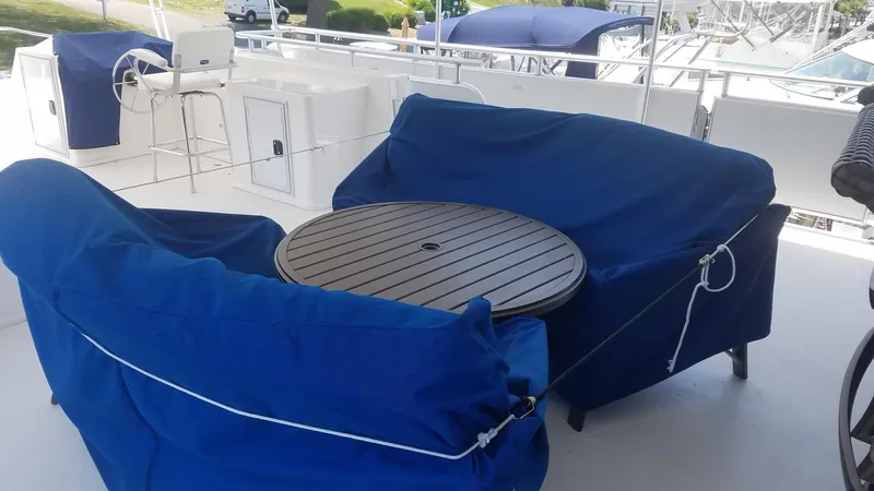 St. Somewhere Yacht Photos Pics Upper deck of 2017 Sumerset houseboat with blue-covered seating and round table.