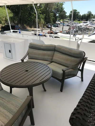 St. Somewhere Yacht Photos Pics Outdoor seating area on 2017 Sumerset houseboat with round table and cushioned bench.