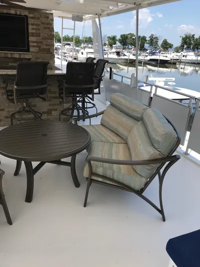 St. Somewhere Yacht Photos Pics 2017 Sumerset houseboat deck with cushioned seating, round table, and bar stools overlooking marina.