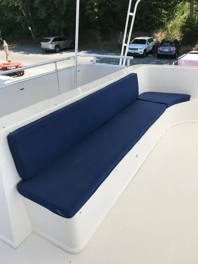 St. Somewhere Yacht Photos Pics Blue cushioned seating on 2017 Sumerset houseboat deck, with parked cars in the background.