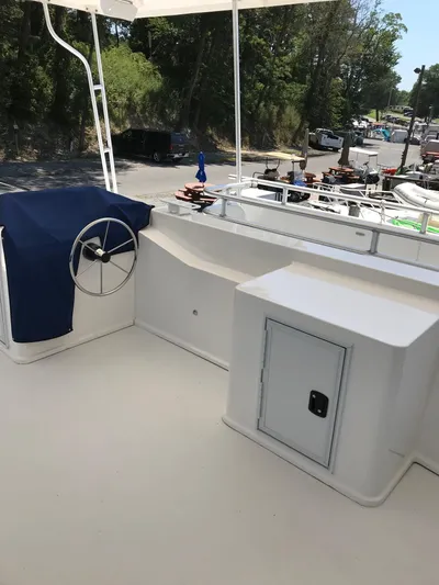 St. Somewhere Yacht Photos Pics 2017 Sumerset houseboat deck with steering wheel, blue cover, and storage compartment.
