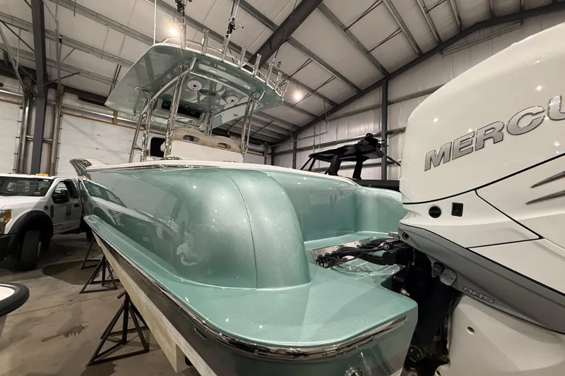  Yacht Photos Pics 2021 Mag Bay 33 CC boat with Mercury engine in a warehouse setting.