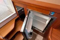 2023 Nimbus T 11 interior with open mini fridge and wooden cabinetry.