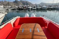 Luxurious 2023 Nimbus T 11 boat with red seating, docked in a scenic marina.