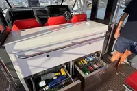 Interior of 2023 Nimbus T 11 boat with red seats and stocked beverage drawers.