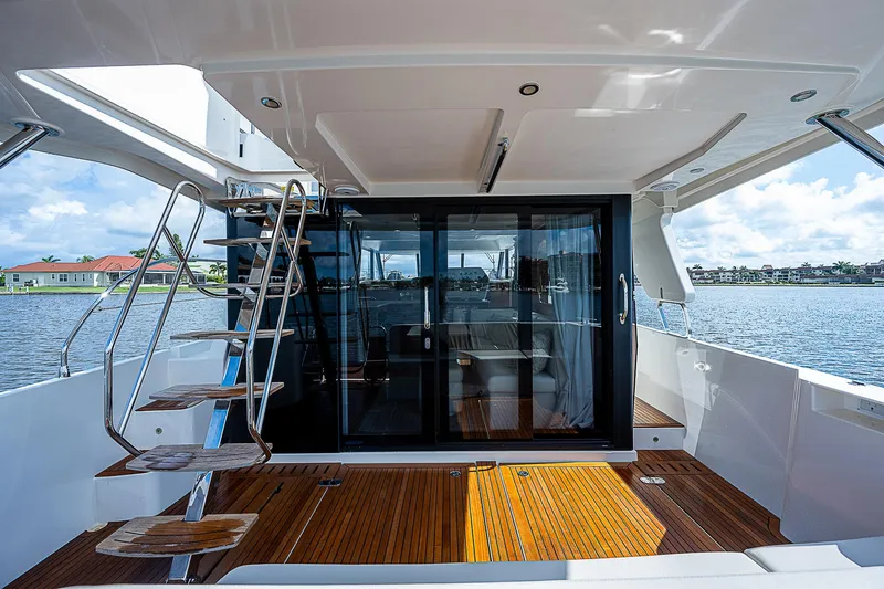 Horizon IV Yacht Photos Pics 2020 Beneteau Swift Trawler 47, rear deck view with wooden flooring and glass doors.