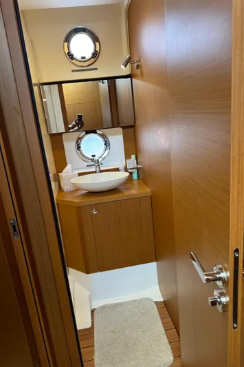 Horizon IV Yacht Photos Pics 2020 Beneteau Swift Trawler 47 bathroom with wooden cabinetry and round porthole window.