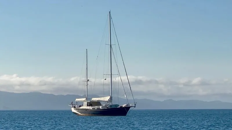  Yacht Photos Pics 1984 Irwin Cutter Ketch sailboat on calm sea with distant mountains.