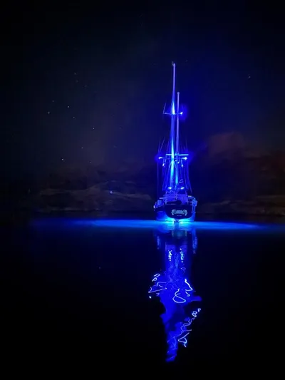  Yacht Photos Pics 1984 Irwin Cutter Ketch illuminated with blue lights on calm water at night.