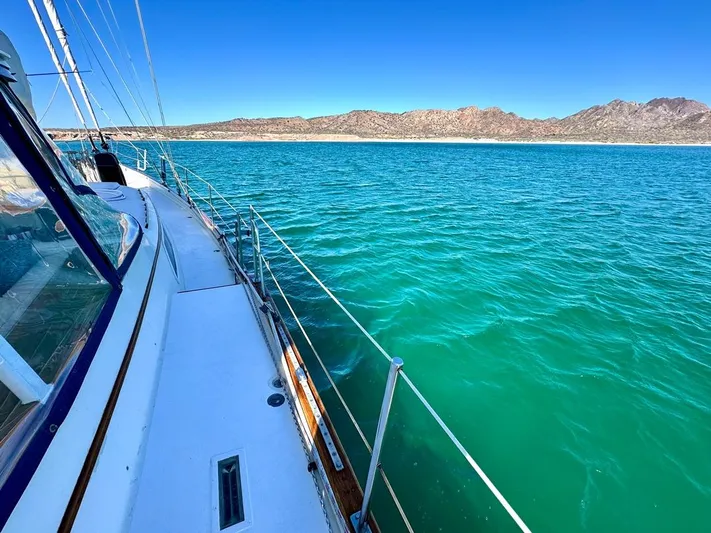  Yacht Photos Pics 1984 Irwin Cutter Ketch sailing on turquoise waters with mountainous coastline in the background.