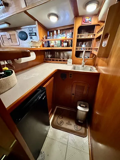  Yacht Photos Pics 1984 Irwin Cutter Ketch yacht kitchen with wood cabinetry, sink, and mini fridge.
