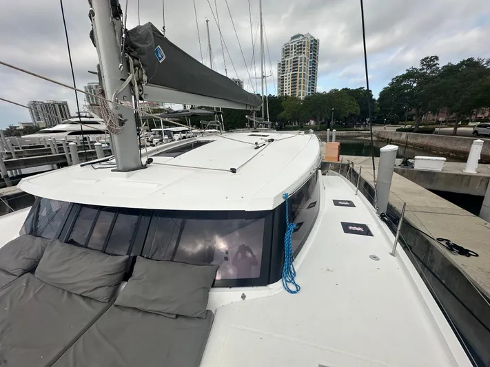 Brave Coquina Yacht Photos Pics 2020 Fountaine Pajot Lucia 40 catamaran docked at a marina with cityscape background.
