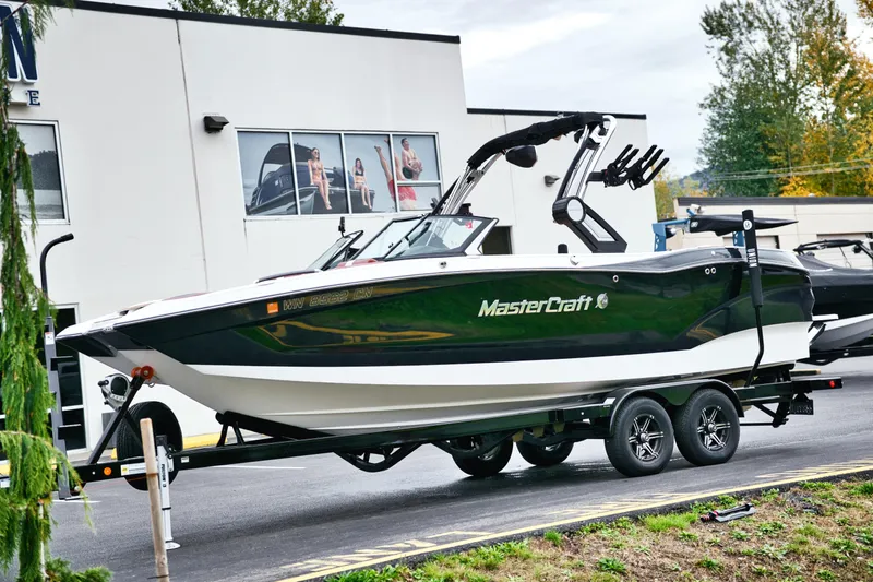  Yacht Photos Pics 2022 MasterCraft X24 boat on trailer outside dealership, showcasing sleek design and modern features.