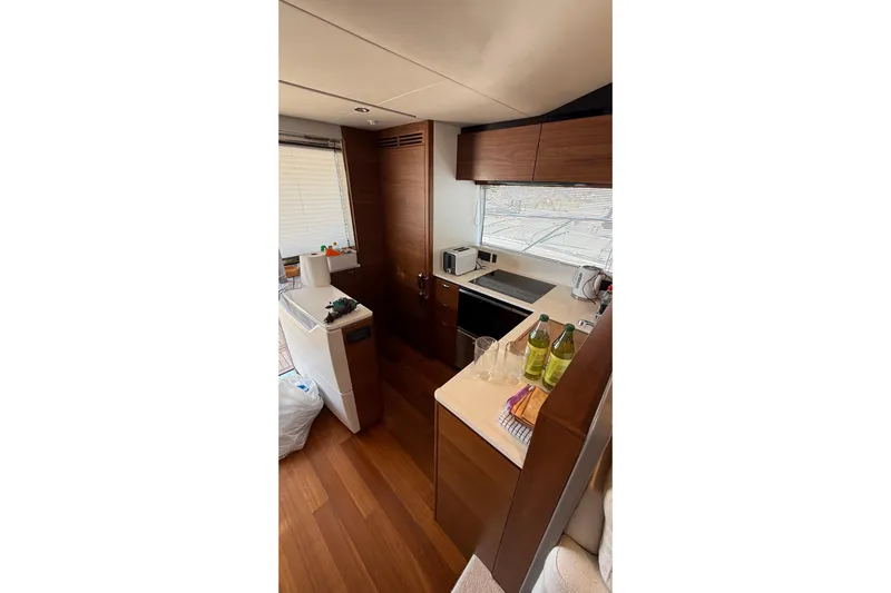 Three Amigos Yacht Photos Pics Modern kitchen interior on a 2021 Princess S62 yacht, featuring wood cabinetry and appliances.