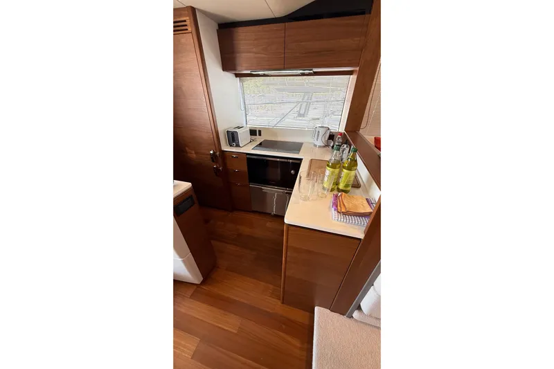 Three Amigos Yacht Photos Pics Modern kitchen interior of 2021 Princess S62 yacht with wooden cabinetry and appliances.