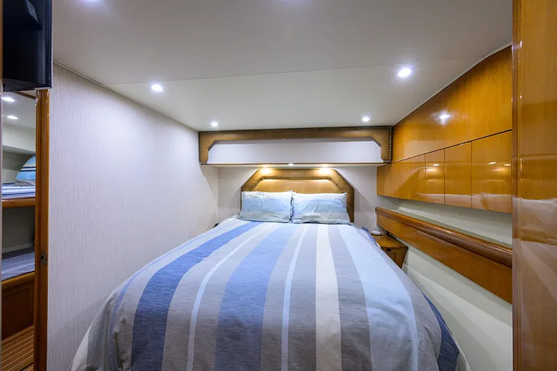 Sea Keeper 9 Yacht Photos Pics Luxurious bedroom interior of 2005 Post 53 Convertible yacht with striped bedding and wooden cabinetry.