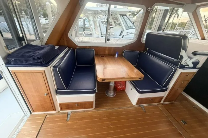 Miracle 2 Yacht Photos Pics Interior of 2006 True North 38 boat with wooden table and navy seating.
