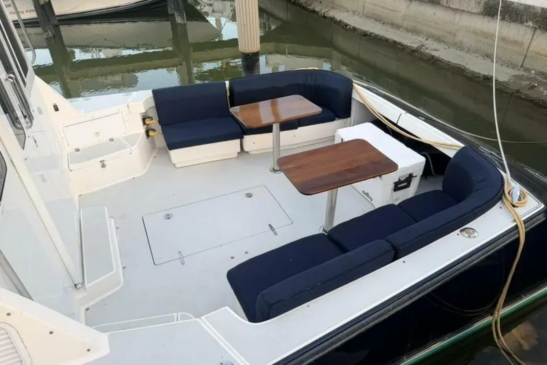 Miracle 2 Yacht Photos Pics Spacious 2006 True North 38 boat deck with cushioned seating and wooden tables.