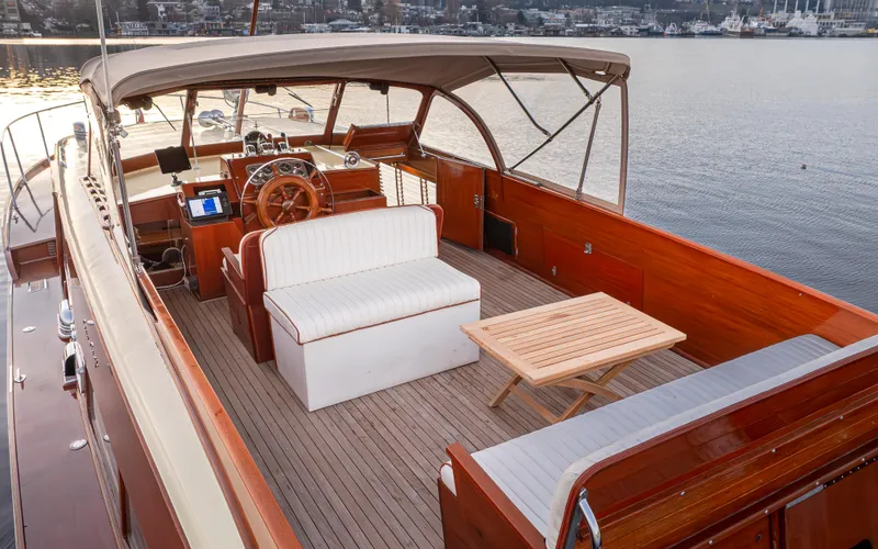 Riva Yacht Photos Pics 1953 Chris-Craft Conqueror boat interior with wooden deck, white seating, and steering wheel.
