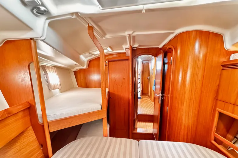  Yacht Photos Pics Interior of 2001 Jeanneau Sun Odyssey 43 DS yacht with wooden finish and cozy sleeping area.