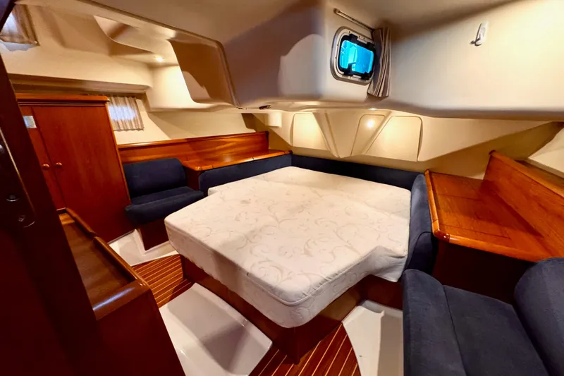  Yacht Photos Pics Luxurious cabin interior of 2001 Jeanneau Sun Odyssey 43 DS yacht, featuring cozy seating and elegant wood finishes.
