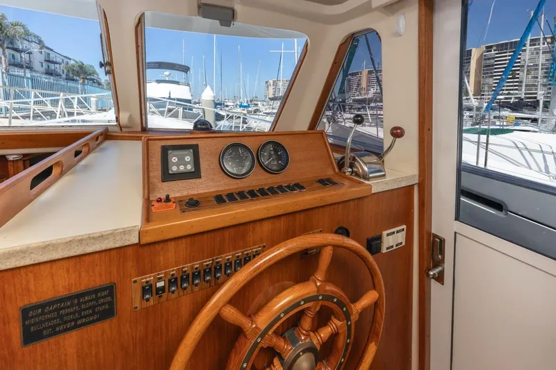 La Woman Yacht Photos Pics 2001 Mainship 390 Trawler helm with wooden wheel and marina view.
