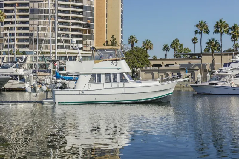 La Woman Yacht Photos Pics 2001 Mainship 390 Trawler docked in a marina with palm trees and buildings.