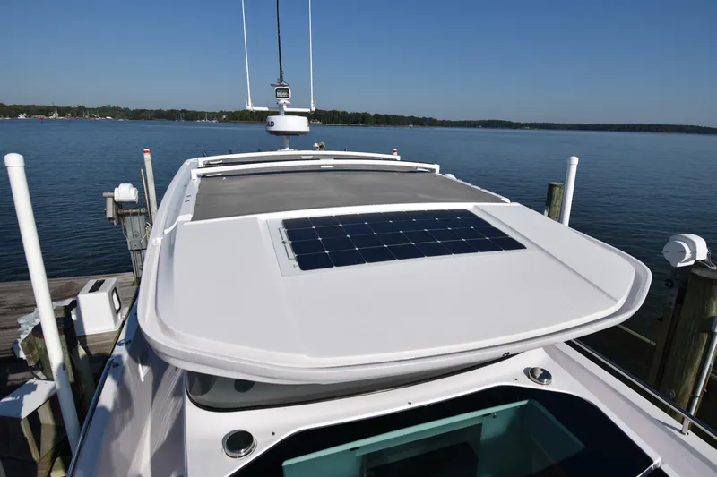 Sundog Yacht Photos Pics 2023 Axopar 37XC Wet Bar with solar panel, docked by a serene lake.