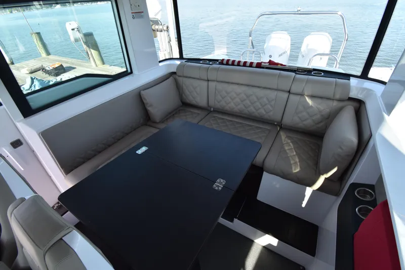 Sundog Yacht Photos Pics 2023 Axopar 37XC Wet Bar interior with cushioned seating and table, overlooking water.