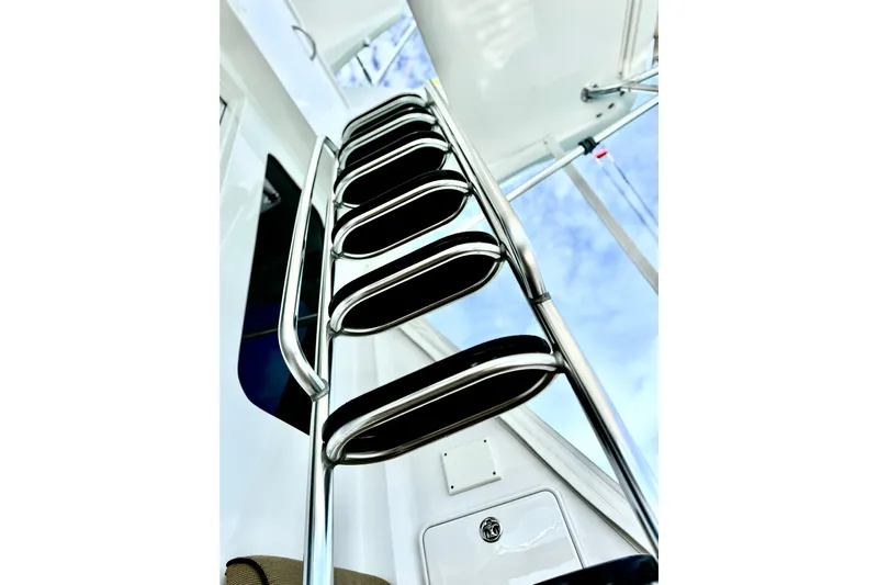 Red Queen Yacht Photos Pics Stainless steel ladder on 2008 Hatteras 64 Convertible yacht against blue sky.
