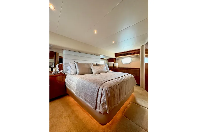 Red Queen Yacht Photos Pics Luxurious bedroom interior of 2008 Hatteras 64 Convertible yacht, featuring elegant bedding and ambient lighting.