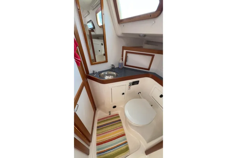 Finesse Yacht Photos Pics 2005 Sabre 386 yacht bathroom with sink, toilet, mirror, and colorful rug.