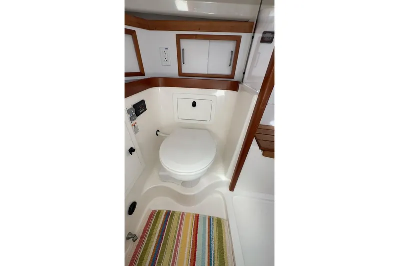 Finesse Yacht Photos Pics 2005 Sabre 386 yacht bathroom with toilet, wooden accents, and colorful striped rug.