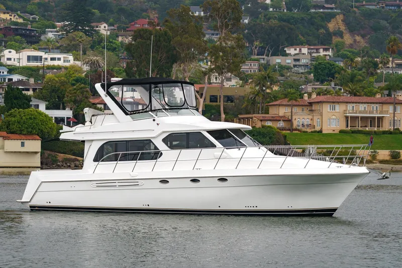 Carrin G Yacht Photos Pics 2008 Navigator 4600 Pilothouse yacht on calm water, with scenic waterfront homes in the background.