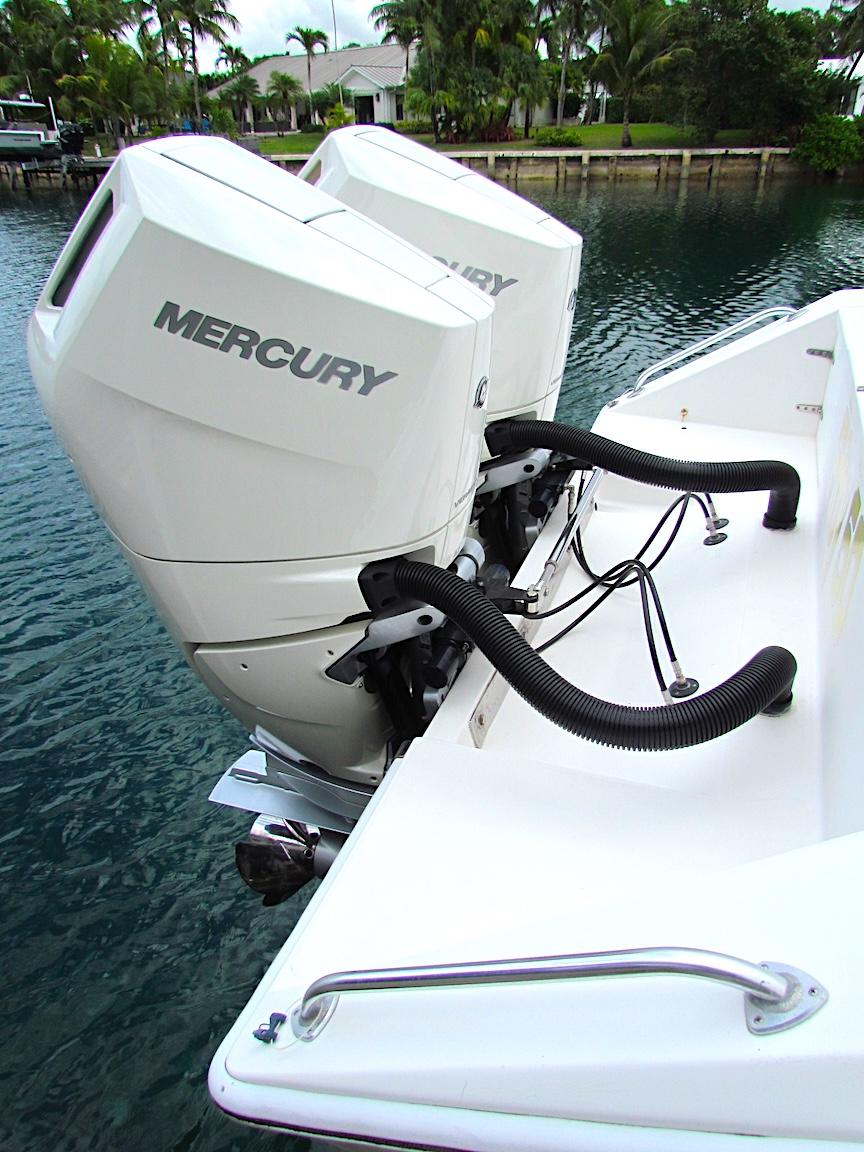 2005 Venture 34 Open boat with dual Mercury outboard engines, docked by the water.
