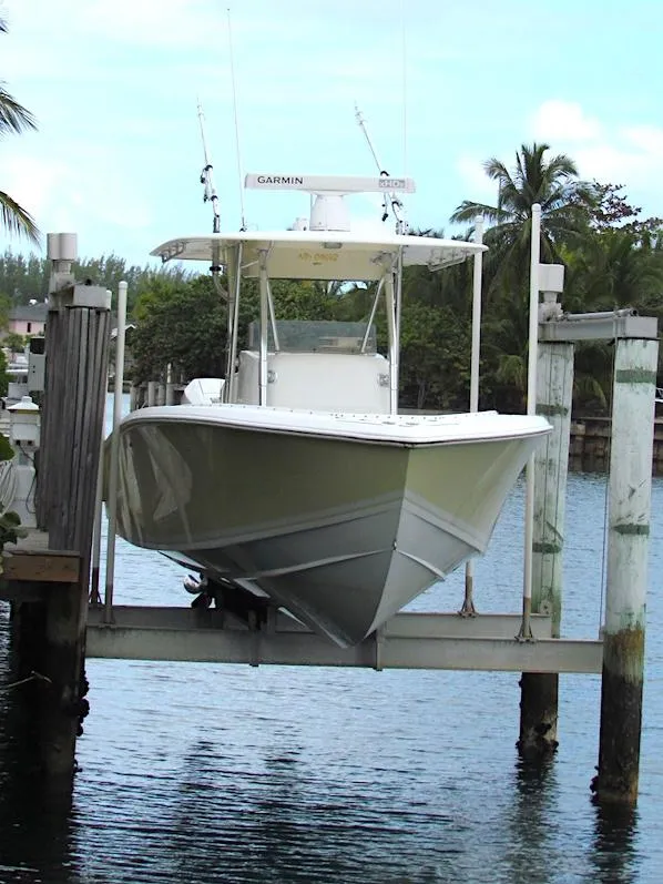 2005 Venture 34 Open boat on lift, surrounded by water and palm trees.