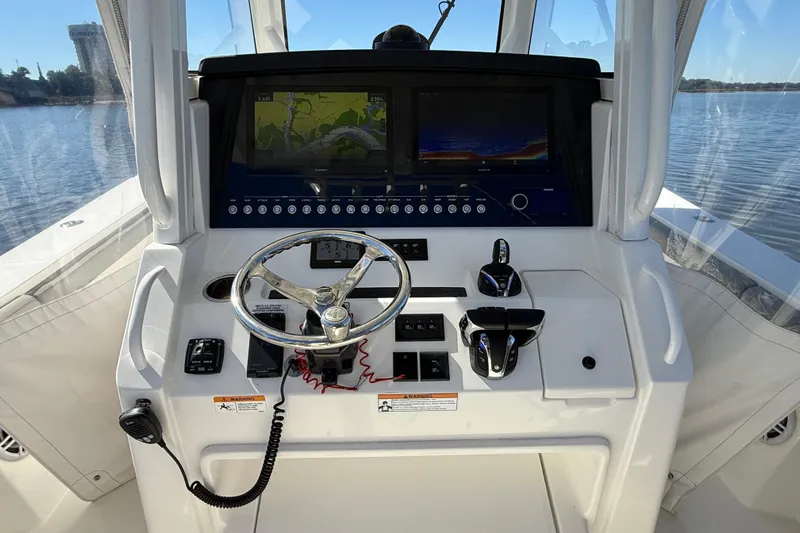  Yacht Photos Pics 2022 Regulator 34 boat helm with dual screens and steering wheel on calm water.