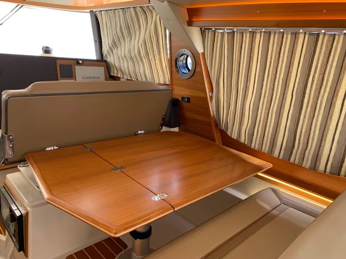 Gadabout Yacht Photos Pics 2024 Ranger Tugs R-29 CB interior with wooden table, striped curtains, and Garmin equipment.