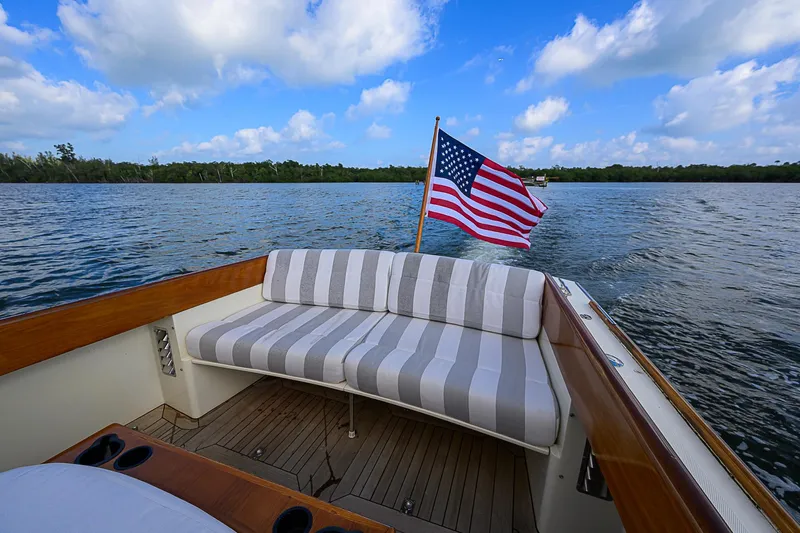 Lucky Town Yacht Photos Pics Hinckley Picnic Boat Classic 2000 with American flag, cruising on a serene lake under blue skies.