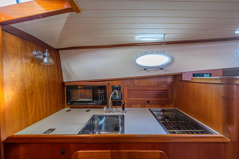 Lucky Town Yacht Photos Pics 2000 Hinckley Picnic Boat Classic interior with wooden cabinetry, sink, stove, and microwave.
